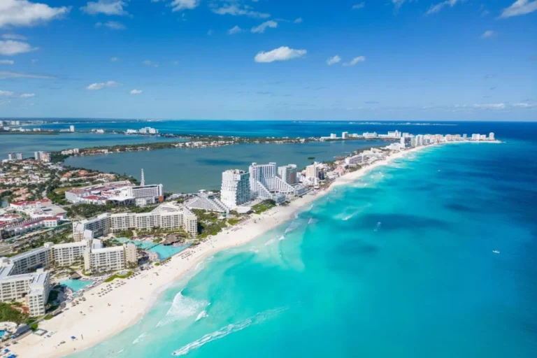 Playa de Cancún en temporada baja con pocos turistas y cielo parcialmente nublado